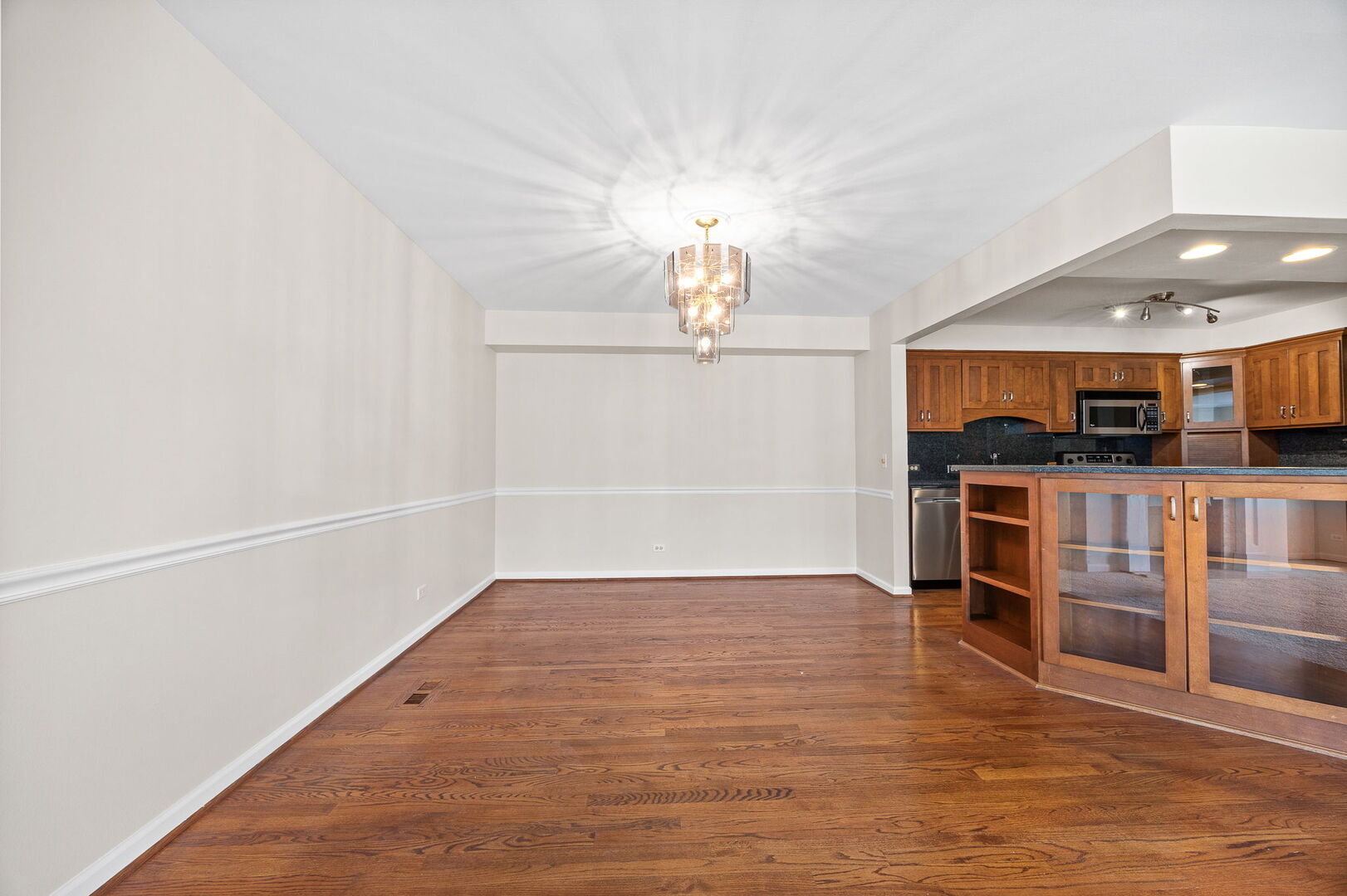 124 Carriage Way Drive, Unit B109 Burr Ridge, IL 60527 - Photo 11 of 31 an empty room with wooden floor kitchen view and a window