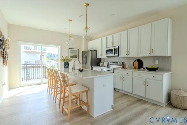 a kitchen with stainless steel appliances granite countertop a stove a sink a microwave a dining table and chairs with wooden floor