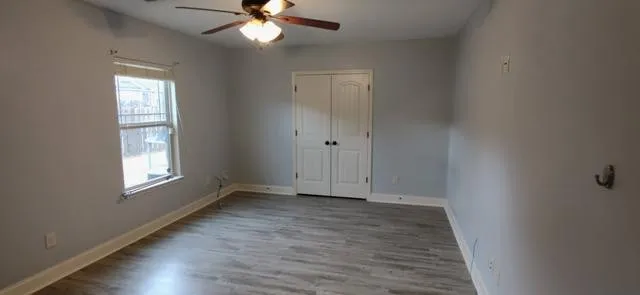 a view of an empty room with wooden floor and a window