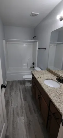 a bathroom with a granite countertop sink and a toilet