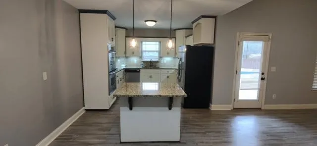an open kitchen with a refrigerator and wooden floor