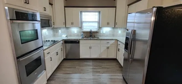 a kitchen with stainless steel appliances granite countertop a refrigerator a stove a sink and a microwave