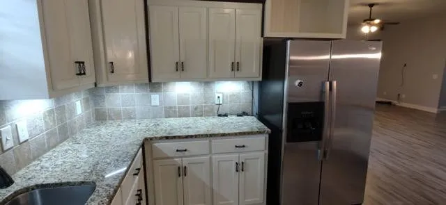a kitchen with granite countertop a refrigerator and a sink