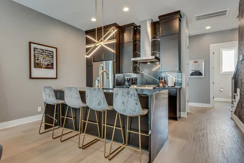 a living room with stainless steel appliances granite countertop a couch a sink dishwasher a living room with couches and potted plants with wooden floor