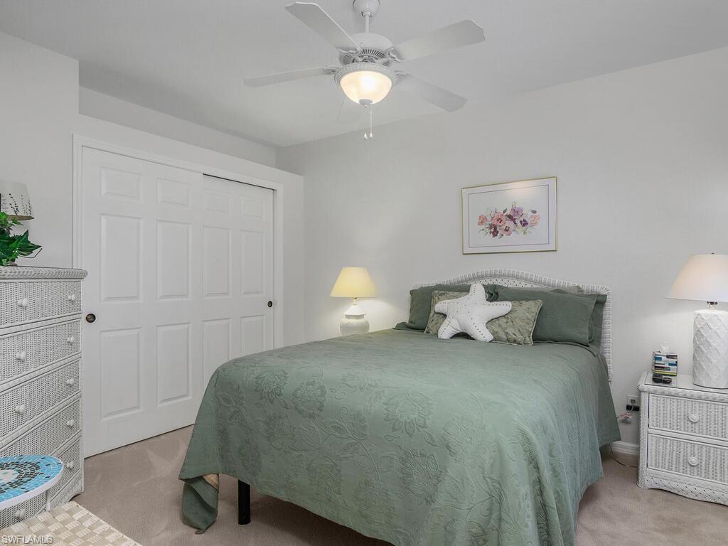 23831 San Marino Road, Unit 102 Estero, FL 34135 - Photo 20 of 39 Bedroom with light colored carpet, a ceiling fan, and a closet