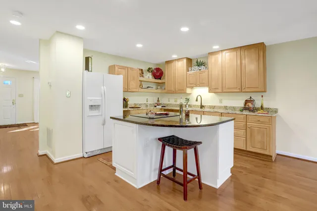 a kitchen with kitchen island stainless steel appliances a sink a stove a refrigerator cabinets and wooden floor