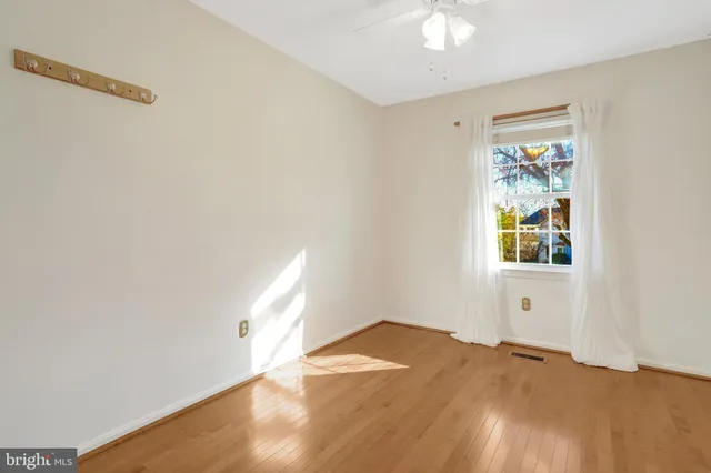 a view of an empty room with wooden floor and kitchen