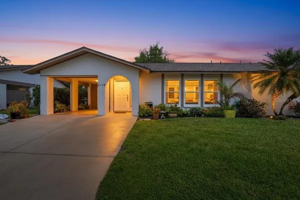 a front view of a house with a yard and potted plants
