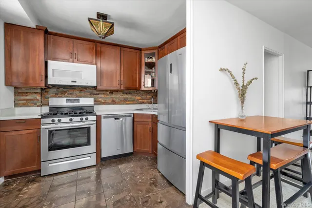 a kitchen with stainless steel appliances granite countertop a stove a refrigerator and a dining table with wooden floor