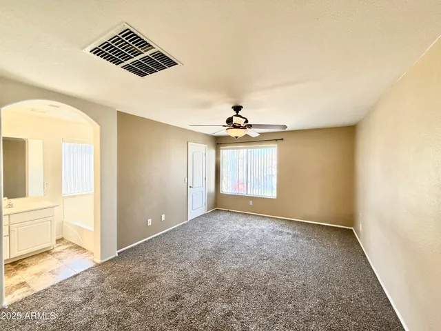 an empty room with windows and ceiling fan