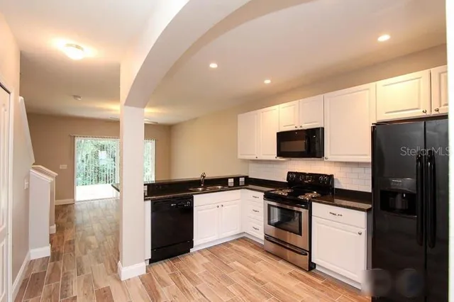 a kitchen with granite countertop a refrigerator stove top oven and sink