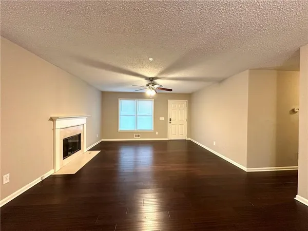 an empty room with wooden floor fireplace and windows