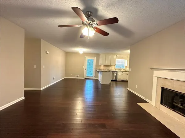 a view of an empty room with wooden floor and a fireplace