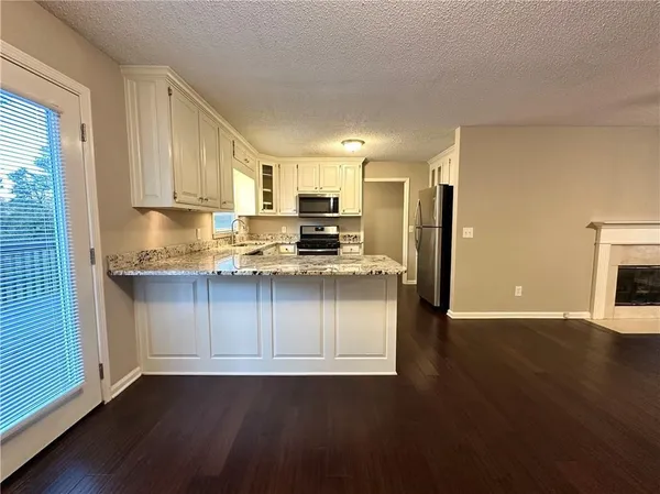 a kitchen with granite countertop wooden floors stainless steel appliances a sink and a window