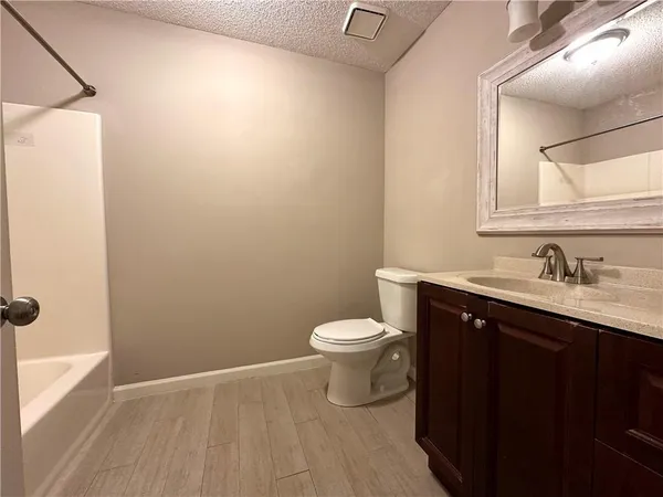 a bathroom with a granite countertop toilet sink and mirror
