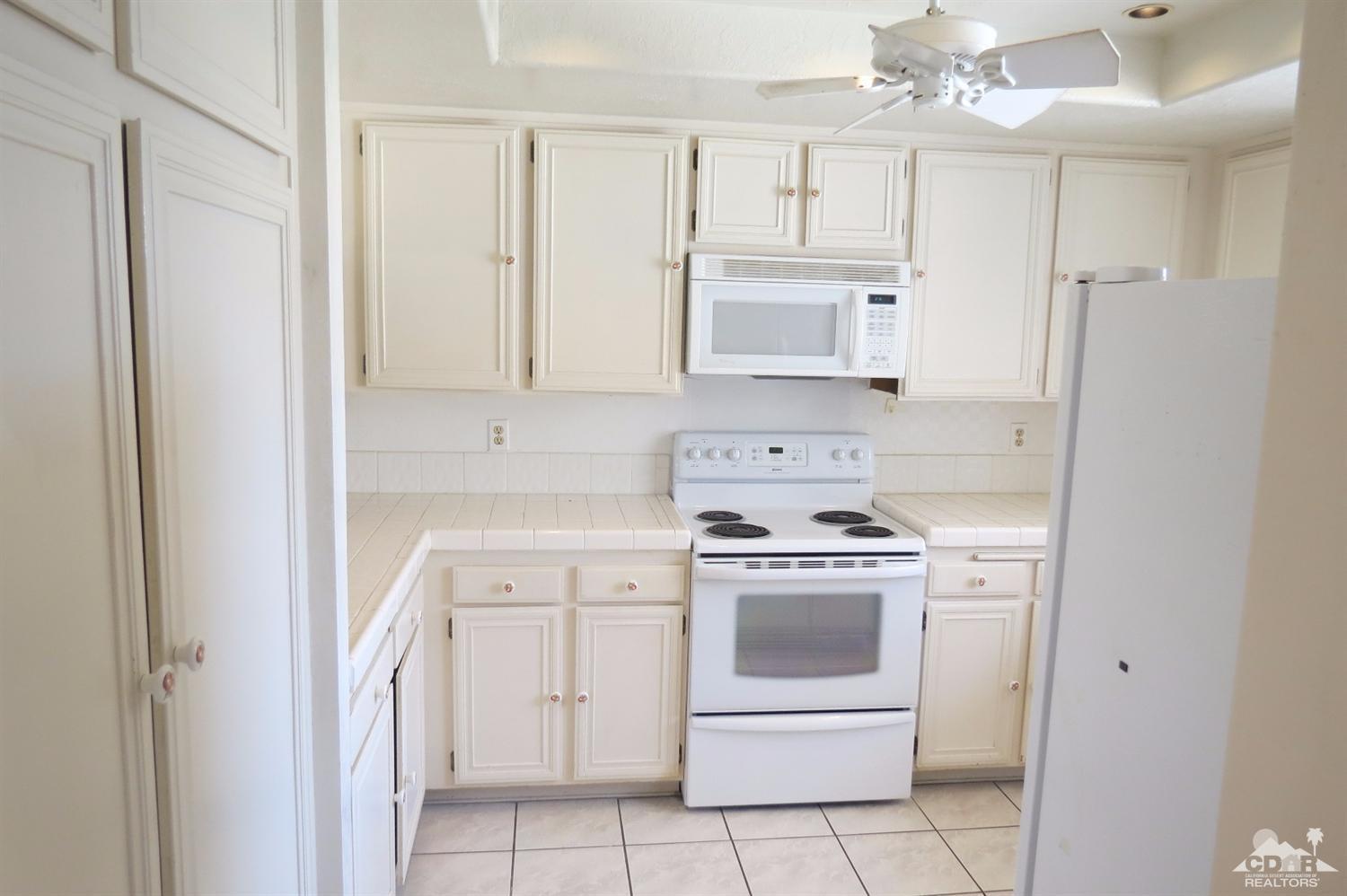 59 La Ronda Drive Rancho Mirage, CA 92270 - Photo 11 of 27 a kitchen with white cabinets and white appliances