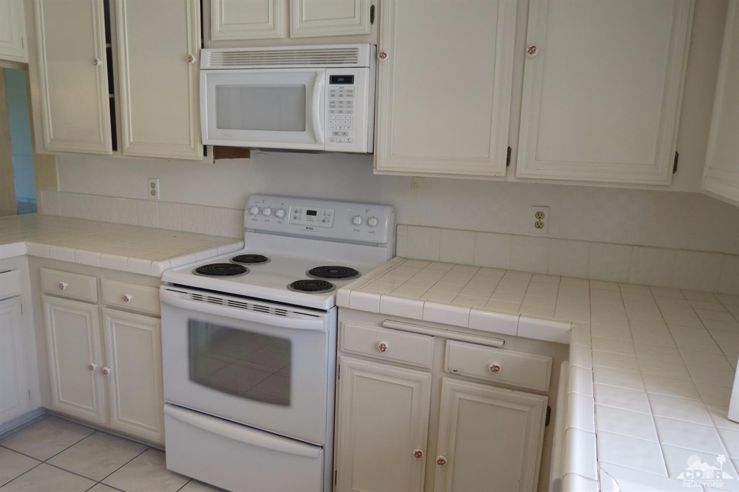 59 La Ronda Drive Rancho Mirage, CA 92270 - Photo 12 of 27 a kitchen with white cabinets and white appliances