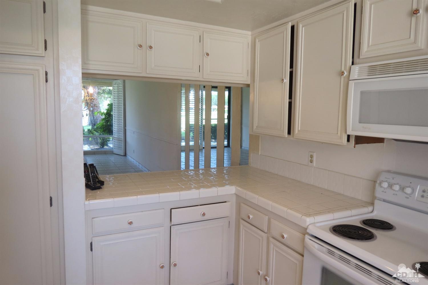 59 La Ronda Drive Rancho Mirage, CA 92270 - Photo 13 of 27 a kitchen with white cabinets and appliances
