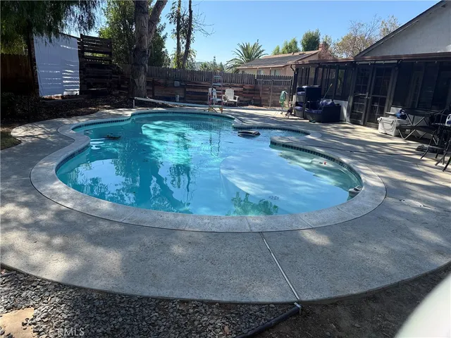 a view of a swimming pool with lawn chairs under an umbrella