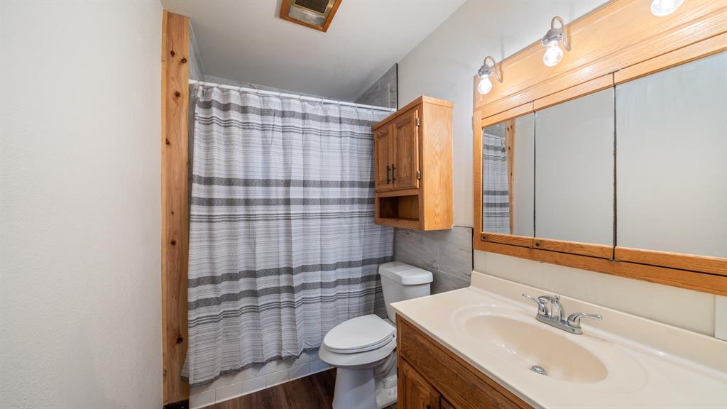 1123 Tbd County Road Fruitvale, TX 75127 - Photo 20 of 31 a bathroom with a sink a toilet a mirror and shower curtain