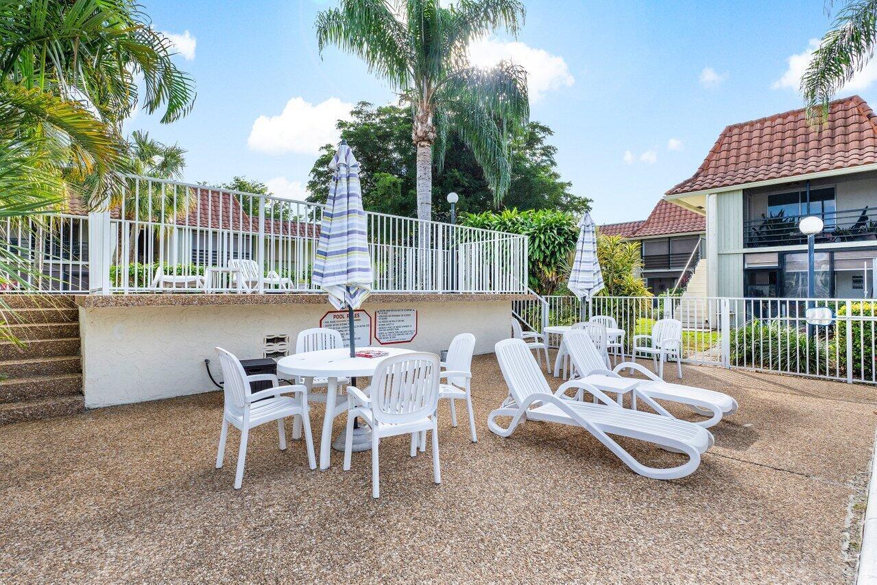 1124 Northwest 13th Street, Unit 204A Boca Raton, FL 33486 - Photo 26 of 30 a view of a patio with a table chairs and backyard