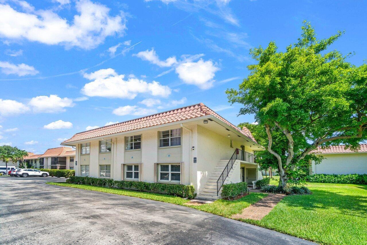1124 Northwest 13th Street, Unit 204A Boca Raton, FL 33486 - Photo 30 of 30 a view of a white house next to a yard with big trees