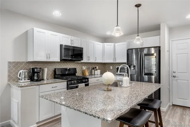 a kitchen with stainless steel appliances granite countertop a stove a sink a microwave a dining table and chairs