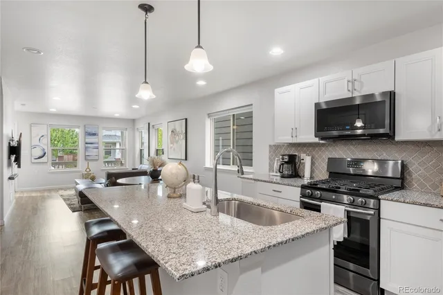 a kitchen with granite countertop a sink a counter space appliances and cabinets