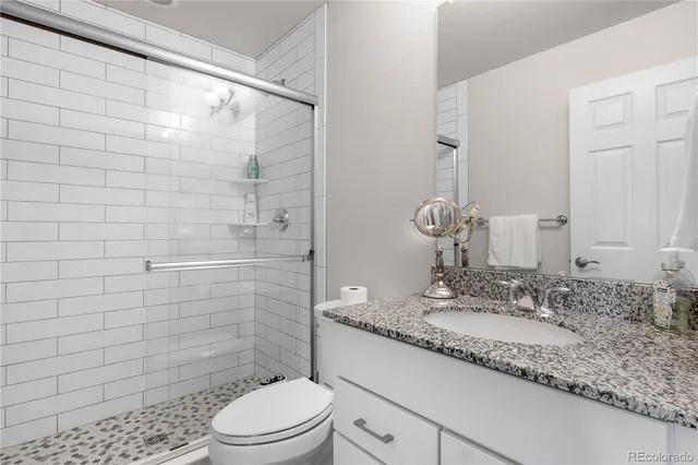 a bathroom with a granite countertop sink toilet and shower