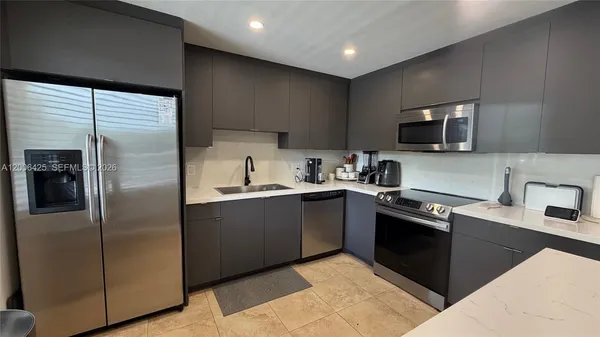 a kitchen with stainless steel appliances granite countertop a refrigerator a sink a stove top oven and wooden floor