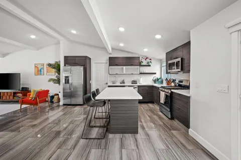 a kitchen with stainless steel appliances a refrigerator sink and wooden floor