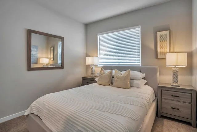 a bedroom with a bed and a lamp on dresser