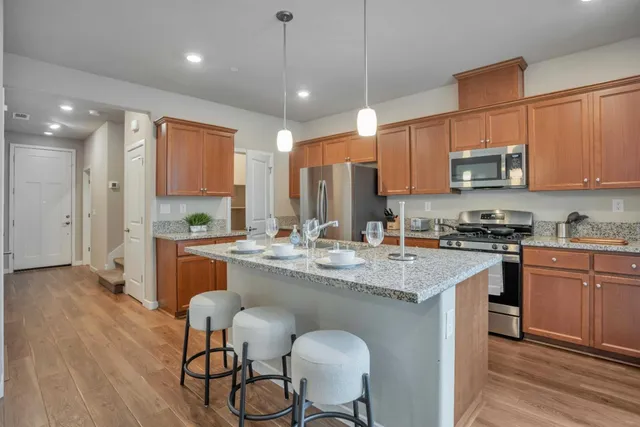 a kitchen with stainless steel appliances granite countertop a stove a sink dishwasher and a refrigerator with wooden floor