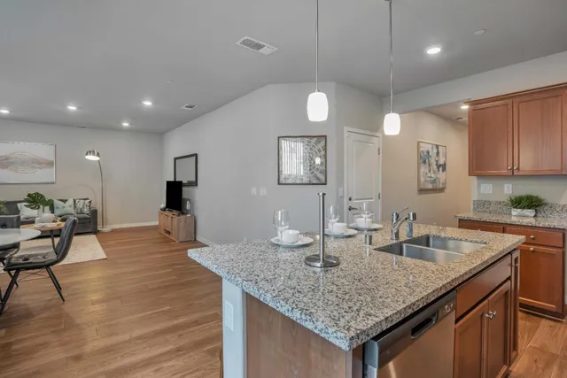 a kitchen with center island a sink dishwasher a stove and a refrigerator with wooden floor