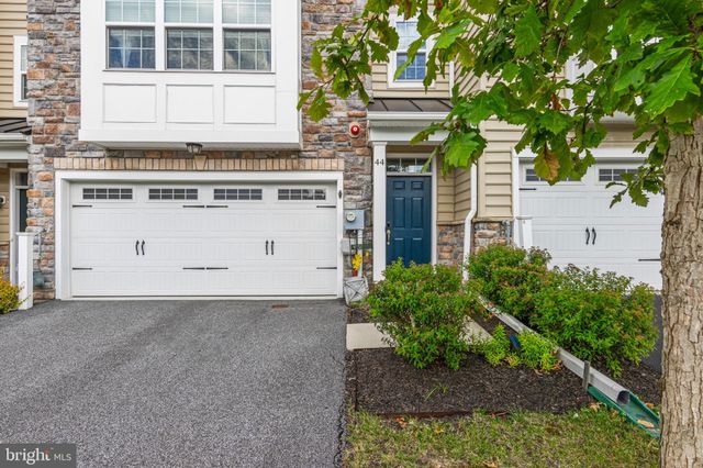 a view of a house with potted plants and a large tree