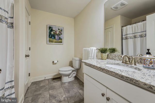 a bathroom with a granite countertop sink mirror vanity and toilet