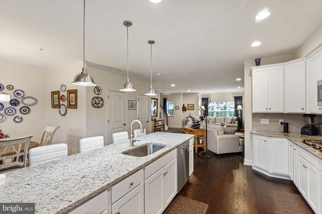 a kitchen with stainless steel appliances granite countertop a stove top oven a refrigerator a sink and a dining table with wooden floor