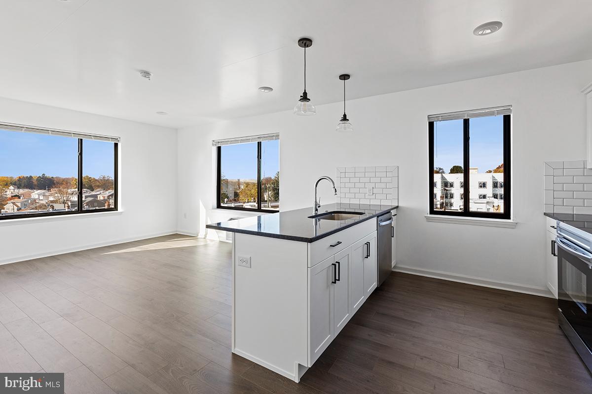 a kitchen with granite countertop a stove a sink and a wooden floors