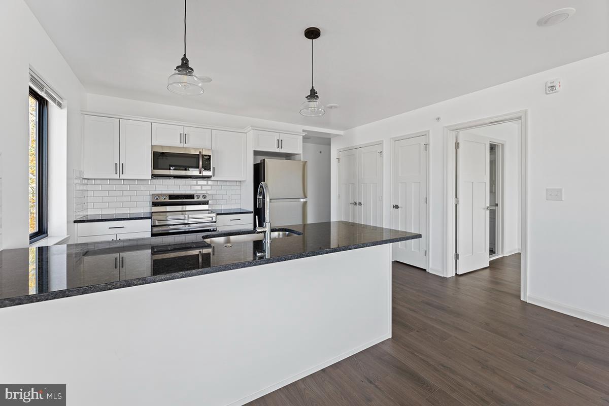 404 Fountain Street, Unit 307 Philadelphia, PA 19128 - Photo 2 of 15 a large kitchen with kitchen island a sink stainless steel appliances and cabinets