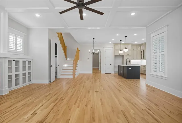 a large empty room with wooden floor and a ceiling fan