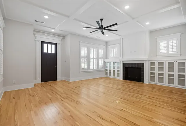 a view of an empty room with window and wooden floor