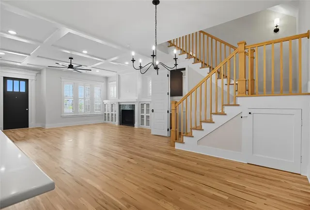 a view of an empty room with wooden floor staircase and a kitchen