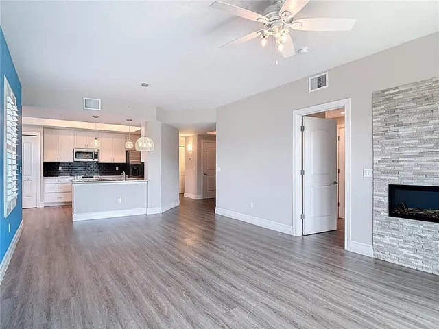 a view of an empty room with wooden floor and a fireplace