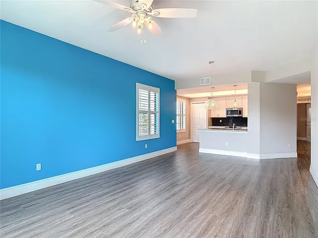an empty room with wooden floor fan and windows