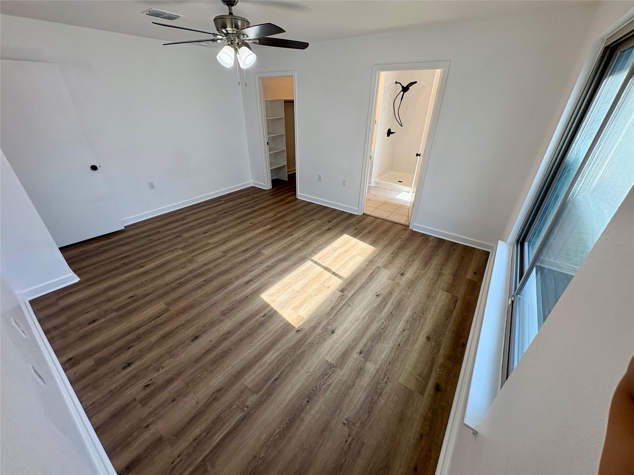 8003 Bannock Lane Austin, TX 78747 - Photo 19 of 40 Master bedroom featuring dark wood-style floors, a spacious closet, ceiling fan, and ensuite bathroom