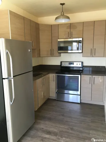 a kitchen with stainless steel appliances granite countertop a refrigerator a stove and a microwave