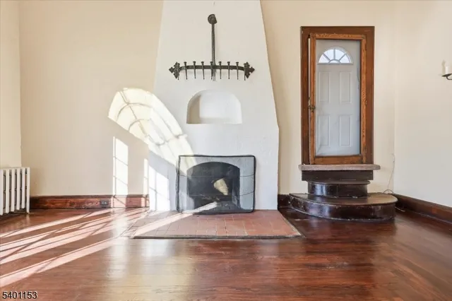 a view of a livingroom with wooden floor a fireplace and windows