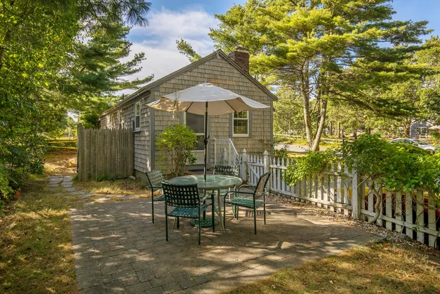 a patio with table and chairs and potted plants