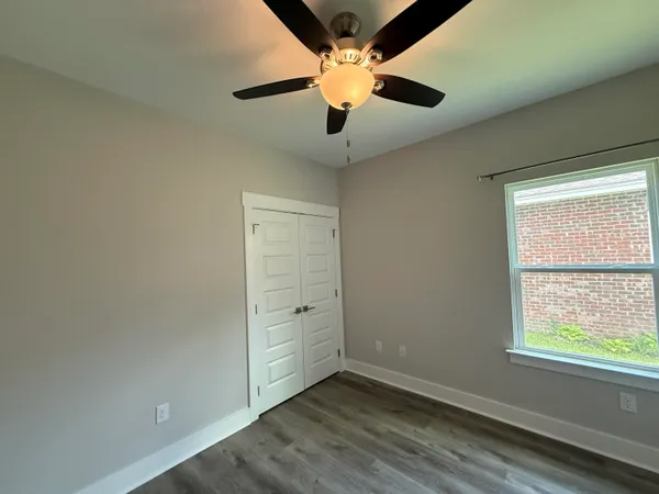 an empty room with windows and ceiling fan