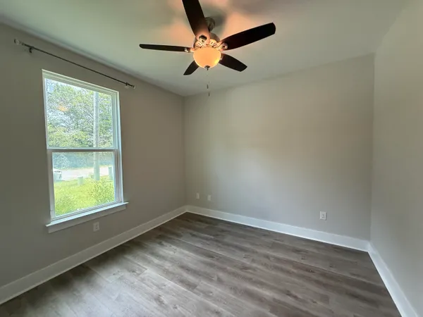 an empty room with a window and a fan